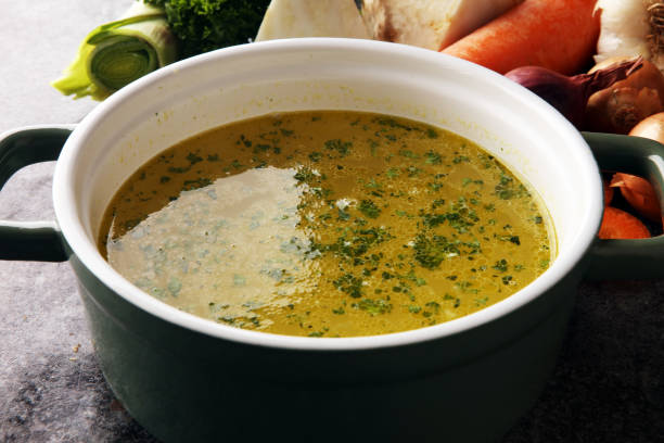 istock Broth with carrots, onions various fresh vegetables in a pot - colorful fresh clear spring soup. Rural kitchen scenery vegetarian bouillon stock 1189103808