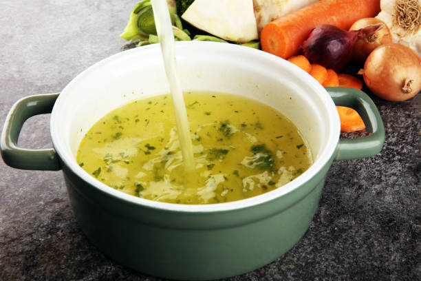 istock Broth with carrots, onions various fresh vegetables in a pot - colorful fresh clear spring soup. Rural kitchen scenery vegetarian bouillon stock 1189104524