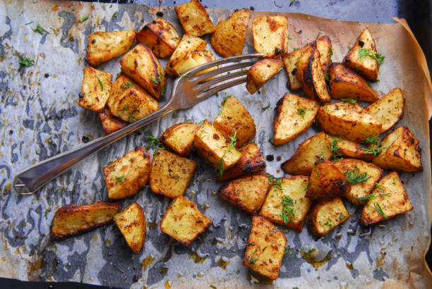 patatas asadas y tenedor - roasted potatoes prepared potato herb food fotografías e imágenes de stock