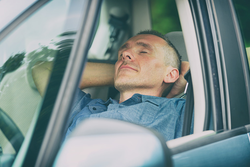 Man sleeping in the car before next part of the journey