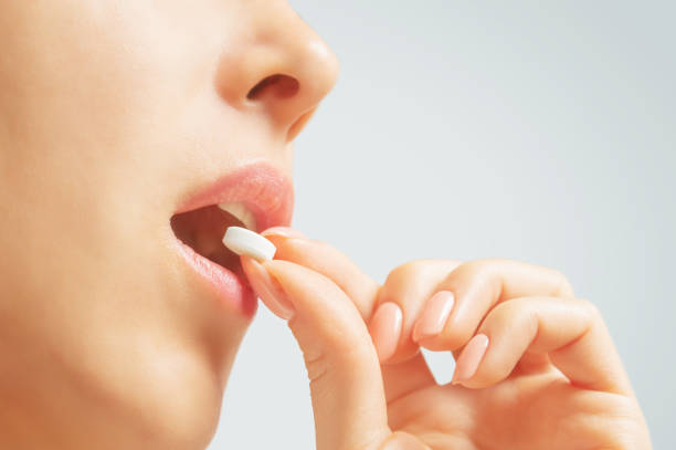 istock Woman taking a white round pill or vitamin. 1189109464