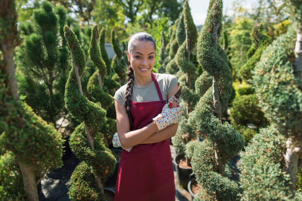 Young charming gardener at the greenhouse, holding hedge clippers and looking at camera