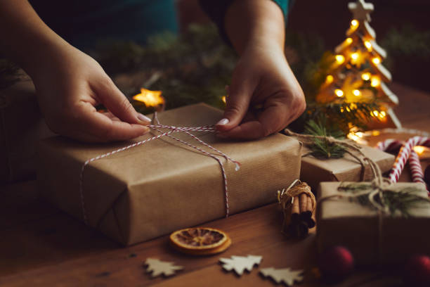 istock Woman packing Christmas gift in paper on table 1189112919
