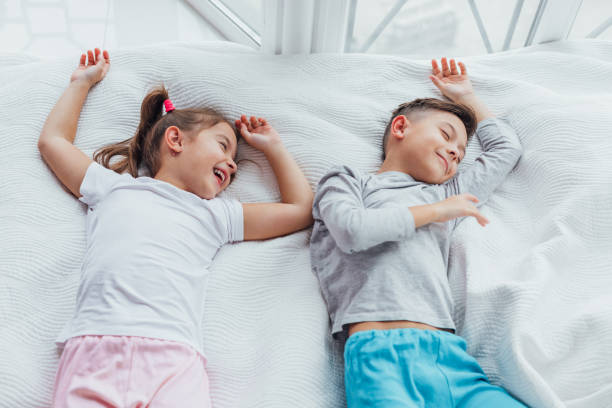 istock Two sweet kids lying on cozy couch, hands over head, ready to take a nap. 1189113044