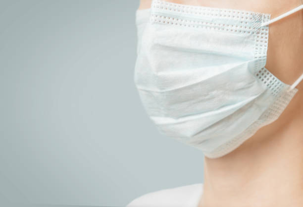Unrecognizable woman in medical protective mask, close-up. stock photo