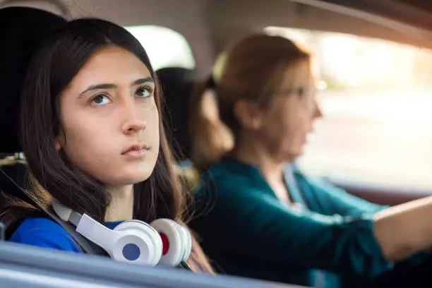 Bad mood teenage girl traveling in a car with her mother