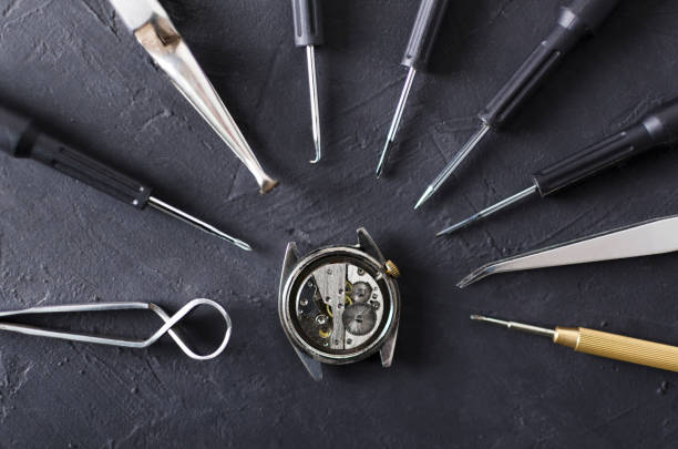 vista dall'alto della cassa dell'orologio aperta e dei diversi tipi di strumenti professionali dell'orologiaio intorno ad essa, superficie nera - watch maker work tool repairing watch foto e immagini stock