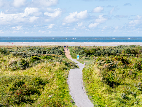 People walking on footpath to North Sea beach of West Frisian island Schiermonnikoog, Netherlands