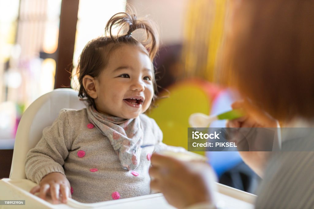 Mother feeding her baby with spoon Baby - Human Age Stock Photo