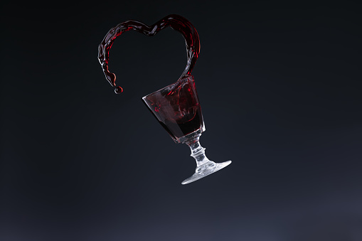 Projection of red wine in the shape of a heart on dark background