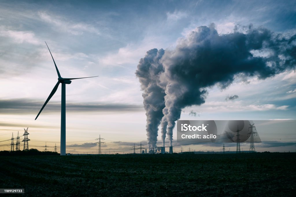 Wind energy versus coal fired power plant Single wind turbine, a coal burning power plant with pollution and electricity pylons in the background. Greenhouse Gas Stock Photo