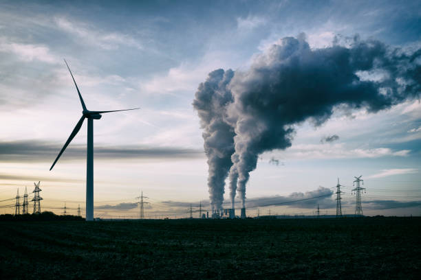 Wind energy versus coal fired power plant Single wind turbine, a coal burning power plant with pollution and electricity pylons in the background. steam photos stock pictures, royalty-free photos & images