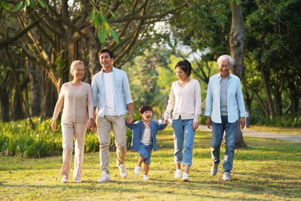 familia de tres generaciones caminando al aire libre en el parque - senior adult fun autumn senior couple fotografías e imágenes de stock