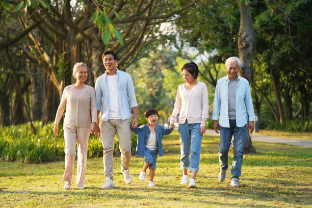 three generation family walking outdoors in park three generation happy asian family walking outdoors in park china chinese ethnicity smiling grandparent stock pictures, royalty-free photos & images