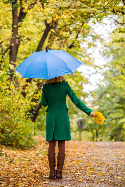 istock Woman holding umbrella and fall leafs  in park 1189131137