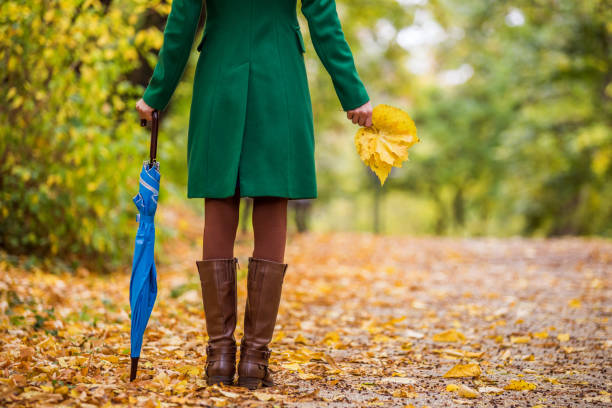 istock Woman in boots holding umbrella and fall leafs 1189131318