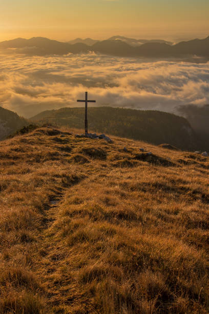 istock Sunlit grass with cross on top of a mountain 1189131858