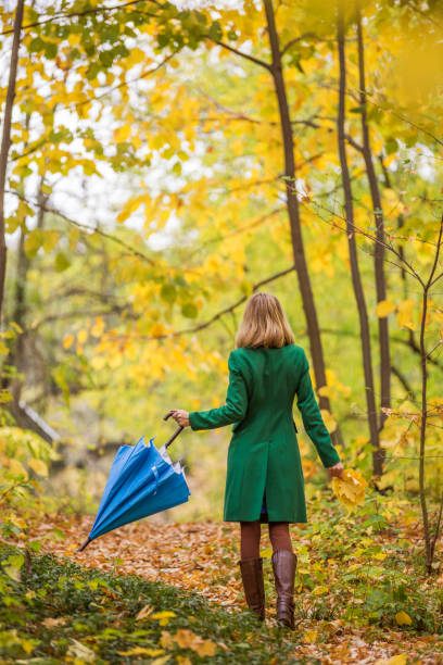 istock Woman with umbrella and fall leafs  walking in  park 1189132600