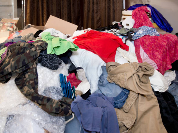 Large messy pile of household items, clothes, boxes, hangers, bubble wrap, toilet paper, pants, shirts, dresses with curtains and mirror in background Close up color photo of extremely messy and disorganized room full of clothing items and random household things including tops, shorts, hangers, boxes, toilet paper, packing materials, bubble wrap, curtains greed stock pictures, royalty-free photos & images