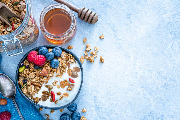 健康的な食べ物:自家製ヨーグルトとグラノーラは、青いテーブルの上から上から撮影。スペースのコピー - breakfast granola dieting food ストックフォトと画像