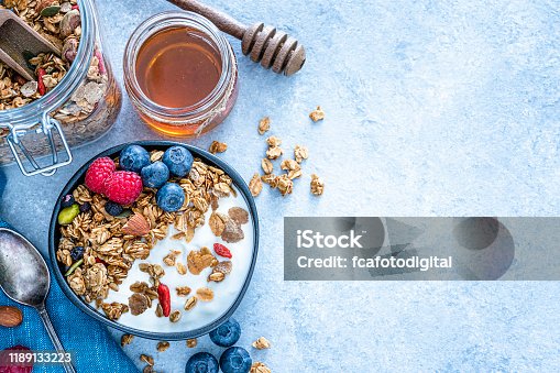 istock Healthy food: homemade yogurt and granola shot from above on blue table. Copy space 1189133223