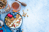 Healthy food: homemade yogurt and granola shot from above on blue table. Copy space