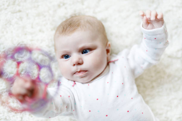 白い背景にカラフルなボールのおもちゃで遊ぶかわいい愛らしい新生児。生まれたばかりの子供、カメラを見ている小さな女の子。家族、新しい生活、子供時代、始まりの概念。赤ちゃんの� - portrait germany party bed ストックフォトと画像