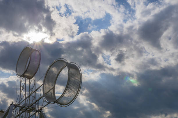 акробат цирковое колесо передач над облачным фоном неба в англии великобритании - carnival spinning built structure frame стоковые фото и изображения