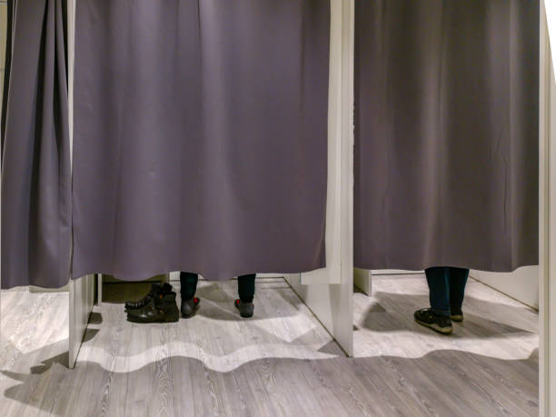 Changing room with closed curtains and feet of two customers Changing room with closed curtains and feet of two customers fitting room stock pictures, royalty-free photos & images