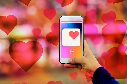 Finger of woman pushing heart icon on screen in mobile smartphone application.