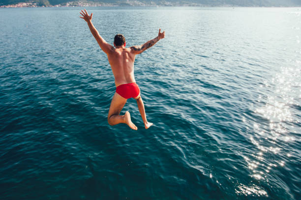 istock Young man jumping from a rock into the sea. 1189142186