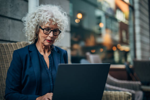 istock Mature lady using laptop in sidewalk cafe 1189143130