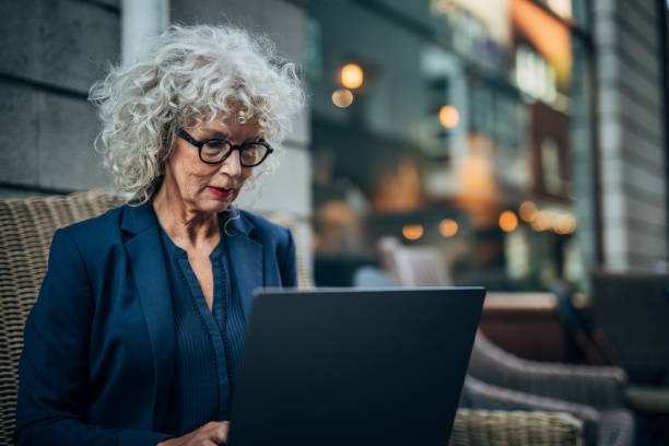 istock Mature woman using laptop in sidewalk cafe 1189143158
