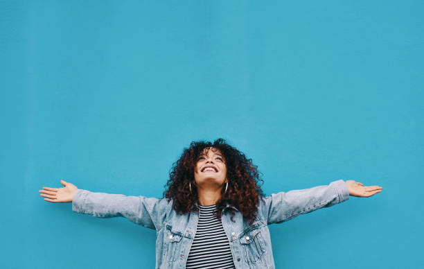 I just wanna celebrate life Cropped shot of an attractive young woman standing with her arms outstretched against a blue background confidence stock pictures, royalty-free photos & images