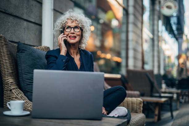 istock Senior woman talking on mobile outdoors in cafe 1189144436
