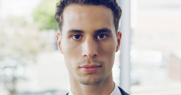Cropped portrait of a handsome young businessman looking serious while standing in a modern office