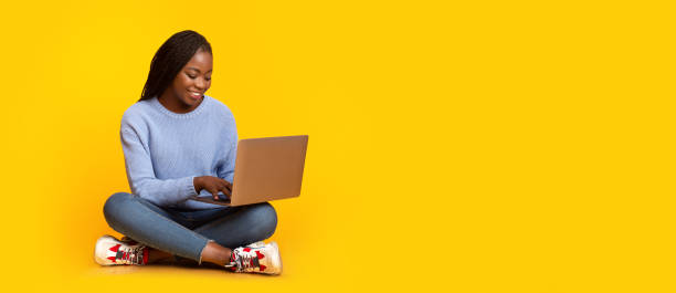 istock Smiling black girl using laptop over yellow background 1189146516