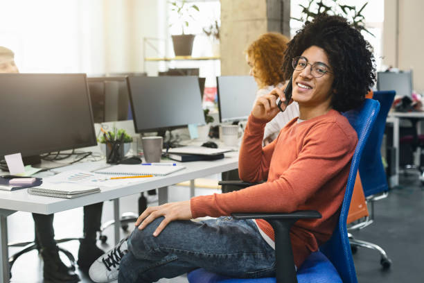 istock Young black guy talking on phone in modern coworking office 1189147357