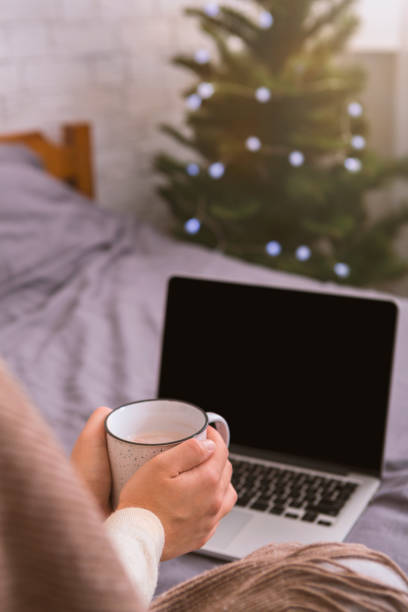 istock Woman with white cup and open new laptop with black blank screen 1189148827