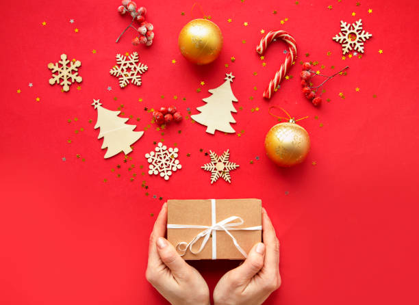 istock Flat lay composition. Woman hands and Christmas accessories and decorations on red background. top view, copy space 1189149838