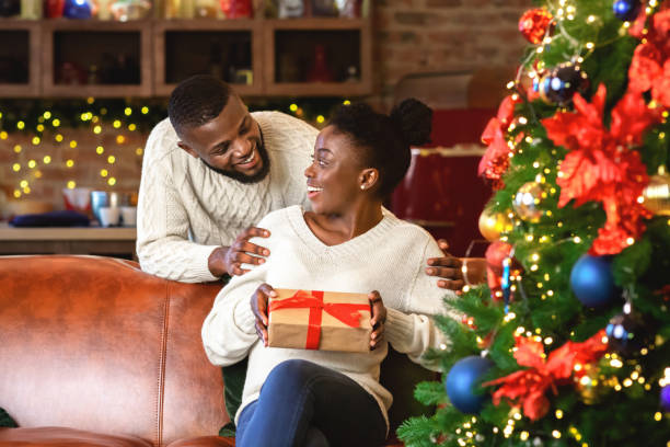 istock Black guy giving his girlfriend gift box, congratulating with Christmas 1189150292