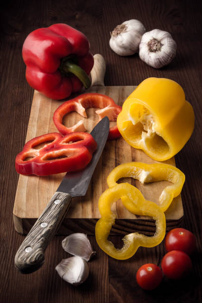 istock Close up on cherry tomatoes, garlic and peppers cut with a knife on a kitchen board on a rustic wooden table. Natural products. Healthy food. Nature and well-being. Healthy diet 1189153131
