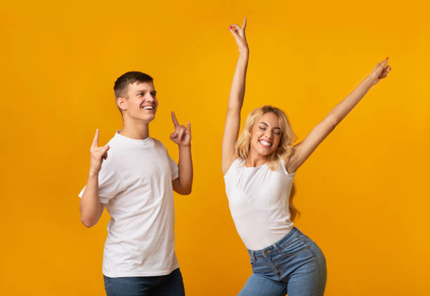 istock Joyful millennial guy and girl dancing in studio over yellow background 1189155164