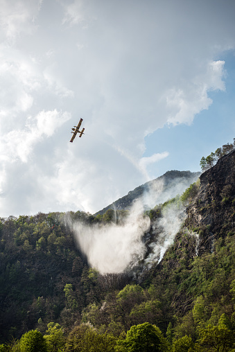 Firefighter airplane putting out a fire on mountain forest