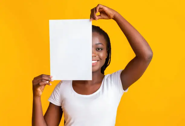 Photo of Black girl covering half of her face with clean paper