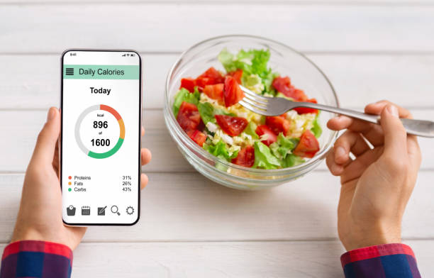 istock Man eating vegetable salad and counting calories on mobile application 1189155991