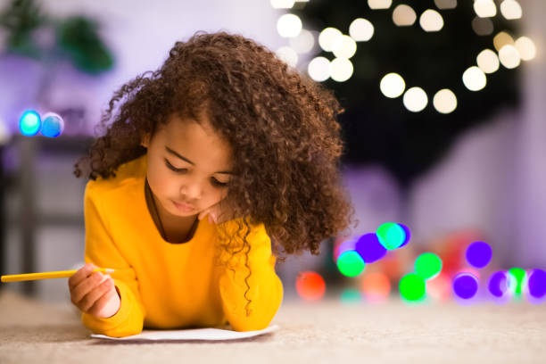 adorabile ragazza africana che scrive lettera a babbo natale - pensive only baby girls baby girls baby foto e immagini stock