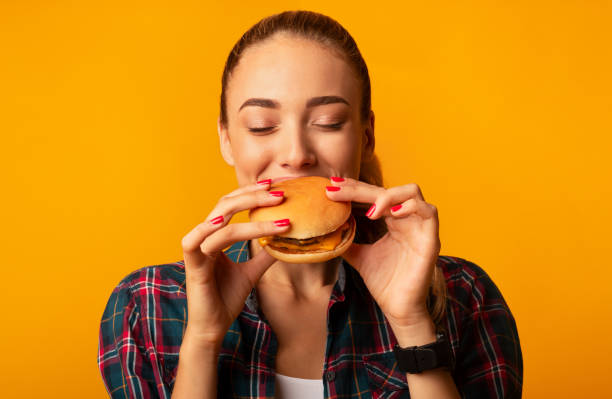 istock Hungry Young Lady Biting Burger Standing, Studio Shot 1189157470