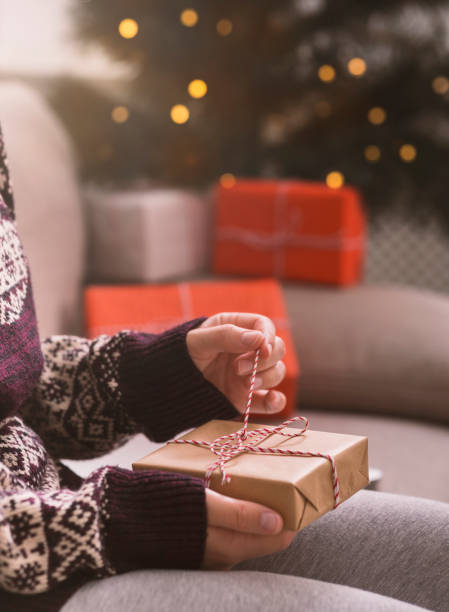 istock Woman unpacking Christmas gift over background with tree 1189159009