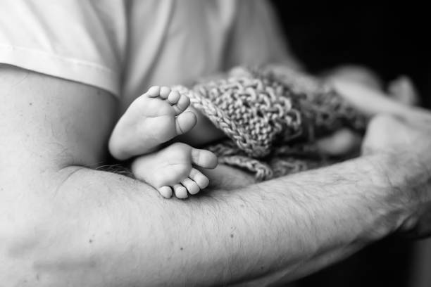 Baby feet in father hands. Black-and-white photo. Baby's feet in black and white stock photo